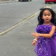 Bryannah joined the competition — help win amazing prizes! child, girl, purple_dress, tiara, bracelet, street, sidewalk, cars, suburban, portrait, smile, curly_hair, accessories, outdoor, young, person, fashion, happy, cute, walking