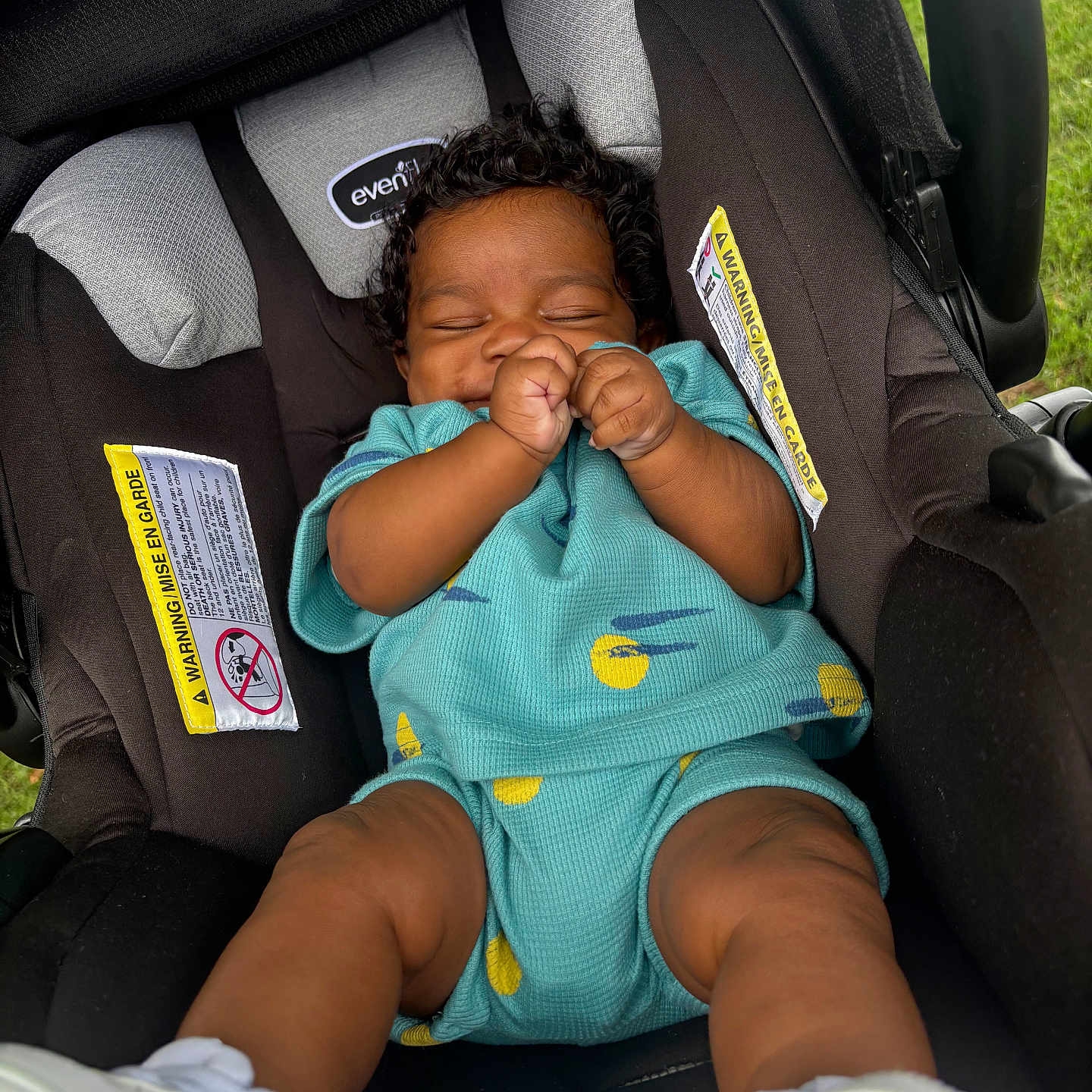 Mazion joined the competition — help win amazing prizes! baby, car_seat, child, closed_eyes, clothing, curly_hair, cute, grass, hands, happy, infant, legs, outdoor, person, seat_belt, sitting, smiling, turquoise_outfit, white_shoes, young