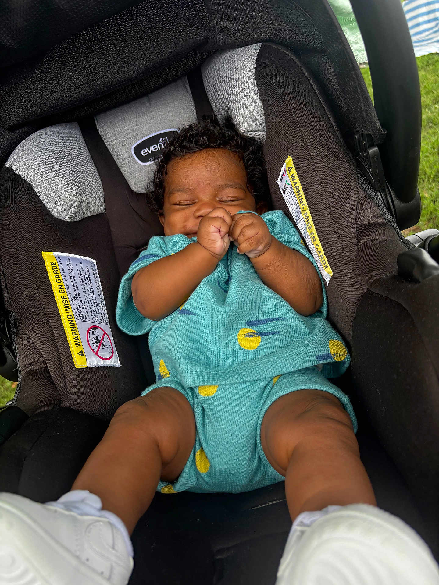 Mazion joined the competition — help win amazing prizes! baby, infant, car_seat, smiling, curly_hair, turquoise_outfit, white_shoes, hands, legs, closed_eyes, happy, outdoor, grass, child, seat_belt, clothing, person, cute, young, sitting