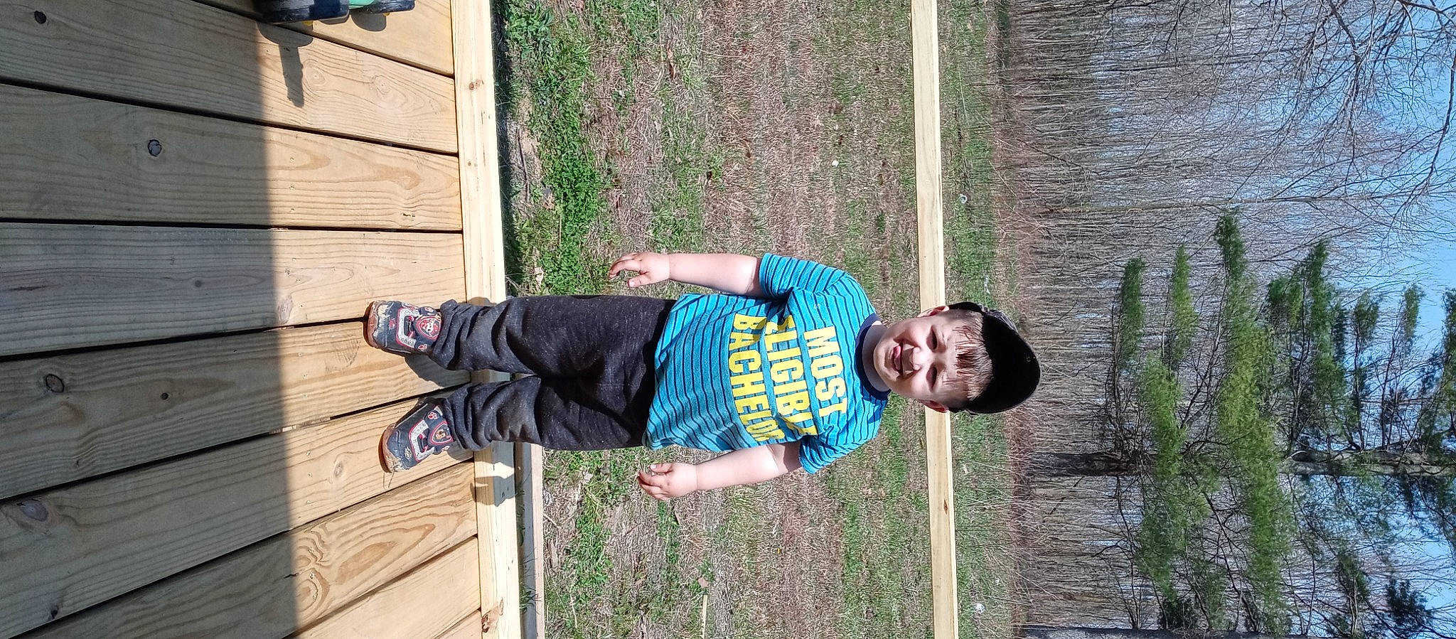 Kolton is registered to the contest to win money with this photo: baby_toddler_clothing, child, fun, grass, happy, joy, leisure, people_in_nature, person, plant, smile, t_shirt, toddler, wood