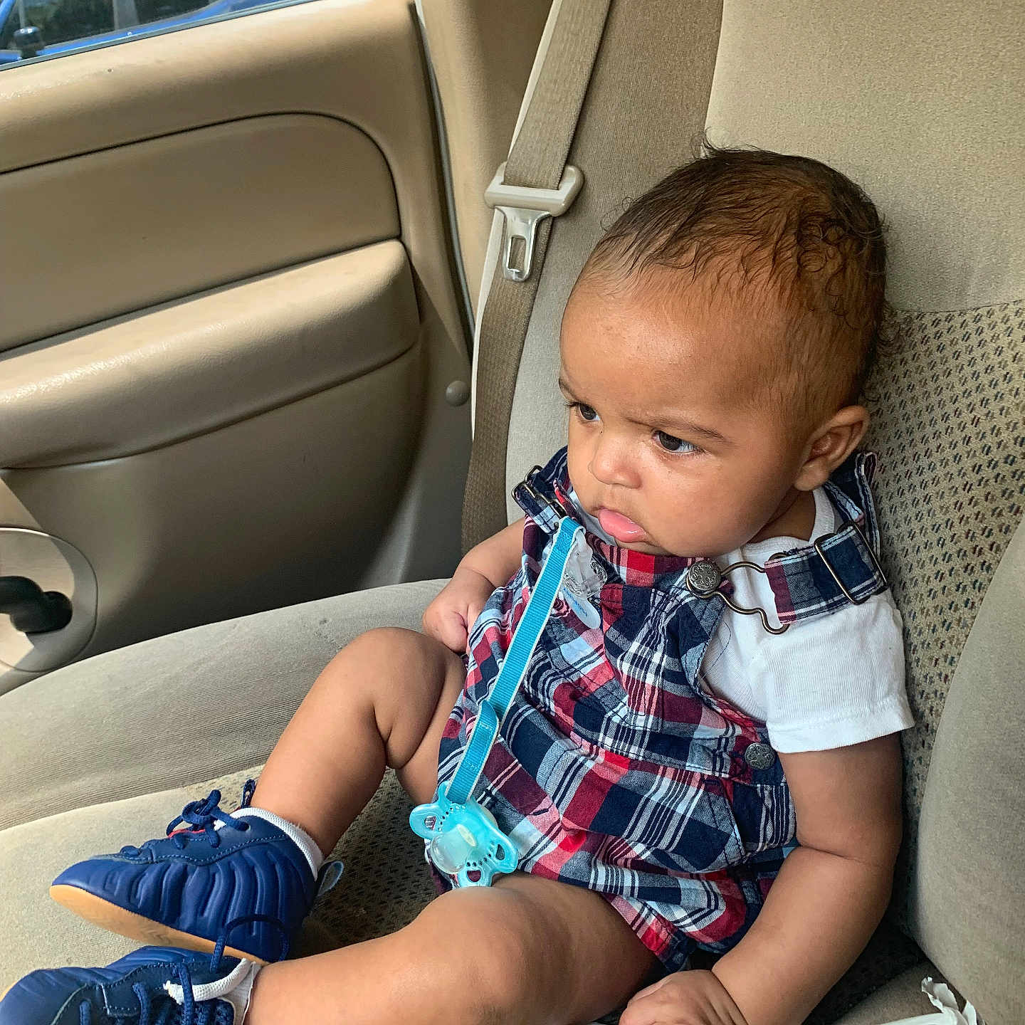 Kaiion joined the competition — help win amazing prizes! baby, blue_sneakers, car_interior, car_seat, casual_wear, child, door, footwear, human, indoors, infant, pacifier, plaid_clothing, seatbelt, serious_expression, side_view, sitting, transportation, window, young_child