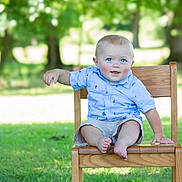 Trenton joined the competition — help win amazing prizes! baby, child, blue_eyes, smiling, wooden_chair, outdoor, grass, greenery, shorts, shirt, person, sitting, happy, young_child, sunlight, nature, park, cute, portrait, summer