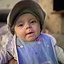 Lilou a rejoint le concours — aidez-le/la à gagner de superbes lots ! baby, infant, face, cap, bib, clothing, cute, indoor, portrait, closeup, child, person, soft_light, curious, smiling, young, toddler, headwear, apparel, background_blur