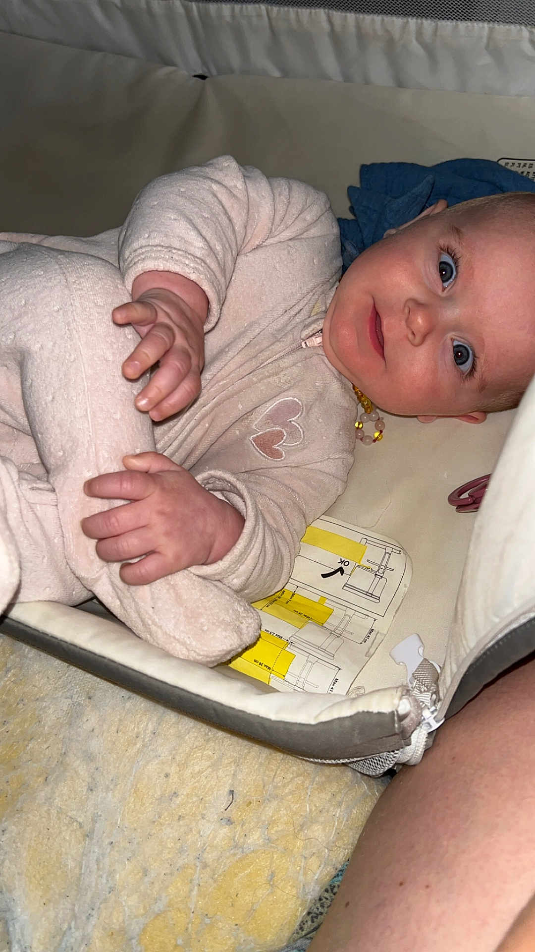 Lilou a rejoint le concours — aidez-le/la à gagner de superbes lots ! baby, infant, onesie, pink_clothing, cushion, playpen, blue_eyes, hand, face, lying_down, blanket, soft_texture, indoor, child, person, newborn, cute, curious, comfort, closeup