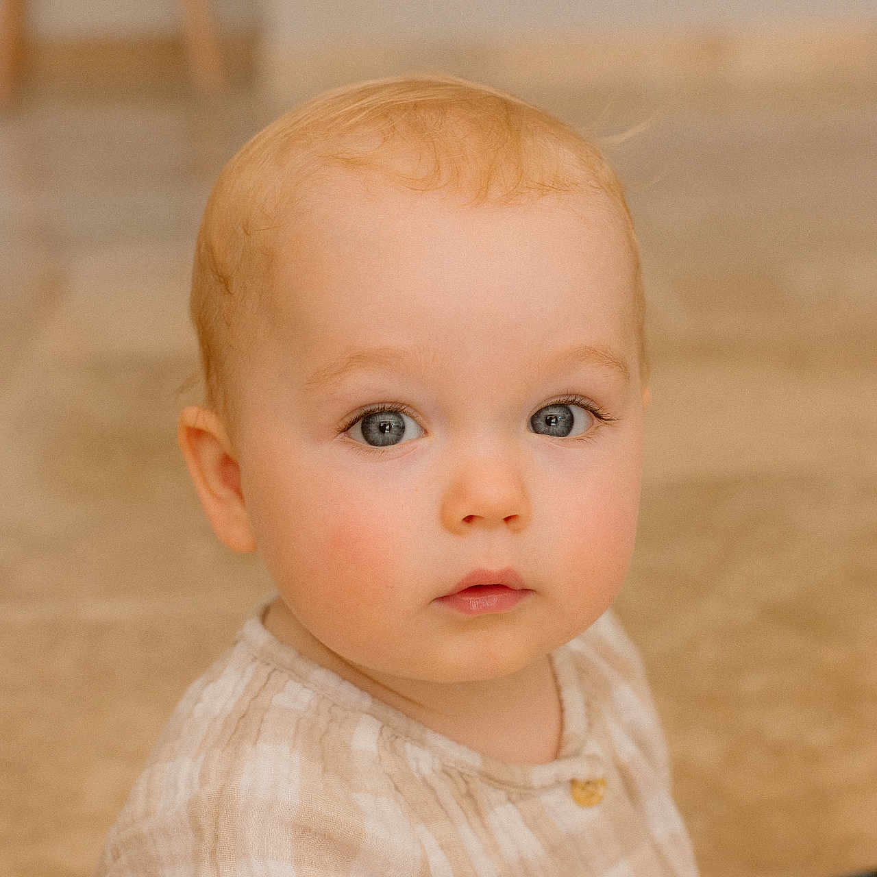 Andrea a rejoint le concours — aidez-le/la à gagner de superbes lots ! baby, blonde_hair, blue_eyes, buttoned_shirt, carpet, child, close_up, curious, cute, expression, face, indoor, infant, person, plaid_clothing, portrait, sitting, skin, soft_lighting, young_child