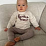 Andrea participe au concours pour gagner de l'argent avec cette photo : toddler, child, couch, sweater, pants, barefoot, indoor, seated, curious, neutral_background, cozy, beige, textile, face, hands, foot, comfort, portrait, casual_clothing, young_child