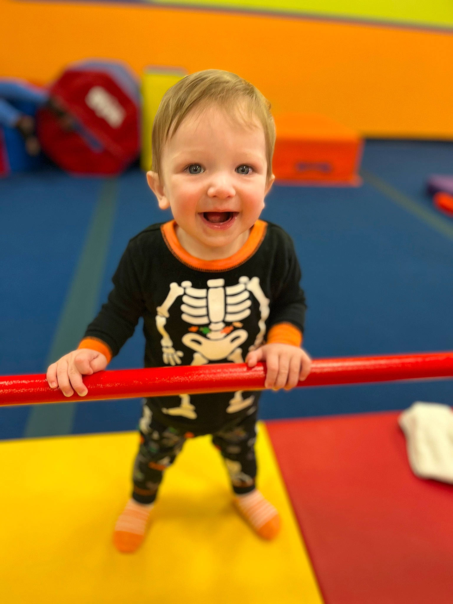 Brody is registered to the contest to win money with this photo: baby_playing_with_toys, child, electric_blue, flooring, fun, happy, human_body, indoor_games_and_sports, joy, leisure, orange, person, play, recreation, recreation_room, room, shorts, smile, standing, t_shirt