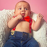 Kalvin is registered to the contest to win money with this photo: baby, child, infant, red_bow_tie, red_suspender, blue_jeans, blanket, pink_background, cute, chubby_cheeks, portrait, sitting, hand, face, expression, clothing, indoor, young, person, cute_baby