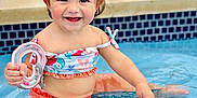 Zaya joined the competition — help win amazing prizes! toddler, child, pool, water, smile, toy, hair_clips, sitting, summer, happy, cute, playful, swimwear, skin, outdoor, fun, baby, person, blue, splash