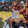 Zaya is registered to the contest to win money with this photo: toddler, child, pony, saddle, outdoor, party, tent, grass, sunny, smile, person, bracelet, yellow_bow, shirt, bounce_house, glasses, family, celebration, fence, stroller