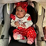 baby, infant, child, car_seat, red_outfit, heart_pattern, bow, headband, pink_socks, sitting, portrait, indoors, vehicle, passenger, wide_eyed, cute, fashion, baby_clothing, car_interior, photography