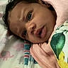 baby, infant, child, portrait, lying_down, blanket, pink_blanket, crib, nursery, bed, close_up, face, dark_hair, brown_eyes, curious, serious_expression, looking_at_camera, indoors, baby_bedding, cozy