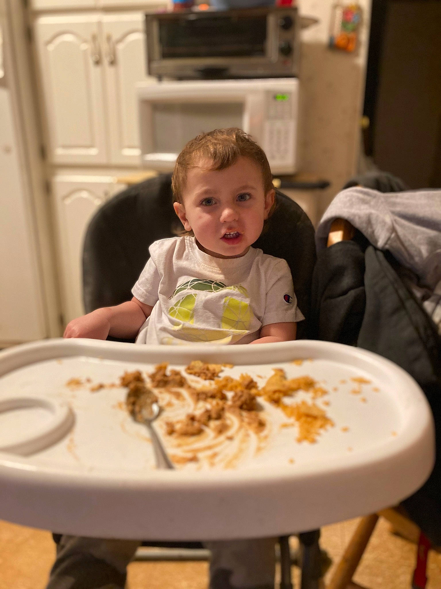 Seth is registered to the contest to win money with this photo: baby, chair, child, comfort_food, cuisine, dish, dishware, door, food, food_craving, home_appliance, kitchen_appliance, person, plate, sharing, sitting, smile, table, tableware, television