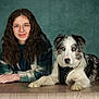 woman, dog, blue_eyes, glasses, curly_hair, plaid_jacket, wooden_table, indoor, portrait, pet, leisure, calm, companion, friendship, furniture, looking_at_camera, casual_clothing, animal, mammal, domestic_animal