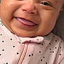 baby, smiling, close_up, face, infant, pink_outfit, heart_pattern, happy, child, cute, portrait, young, skin, eyes, mouth, tongue, clothing, baby_girl, indoors, person