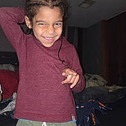Keashawn joined the competition — help win amazing prizes! child, smiling, indoor, braided_hair, maroon_shirt, green_shorts, playful, person, bedroom, blankets, furniture, cozy, happy, casual_clothing, portrait, young, cute, home, fun, posing