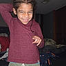 bedroom, blankets, braided_hair, casual_clothing, child, cozy, cute, fun, furniture, green_shorts, happy, home, indoor, maroon_shirt, person, playful, portrait, posing, smiling, young