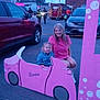 Phoebe is registered to the contest to win money with this photo: barbie, car, casual_clothing, child, dusk, emergency_responders, event, fire_truck, fun, outdoor, pavement, person, photo, pink_car_cutout, playful, smiling, street, toy, vehicle, woman