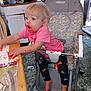 baby, barefoot, cake, child, clutter, curious, expression, face_paint, floor, food, high_chair, indoor, kitchen, leggings, messy, pink_shirt, plastic_high_chair, table, toddler, unicorn_pattern