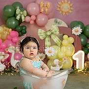 Bea Valeria is registered to the contest to win money with this photo: child, baby, toddler, bathtub, milk_bath, balloons, pink_background, green_balloons, floral, daisies, bow, party_decor, one_sign, portrait, studio_photography, props, flowers, sitting, curious_expression, decorations