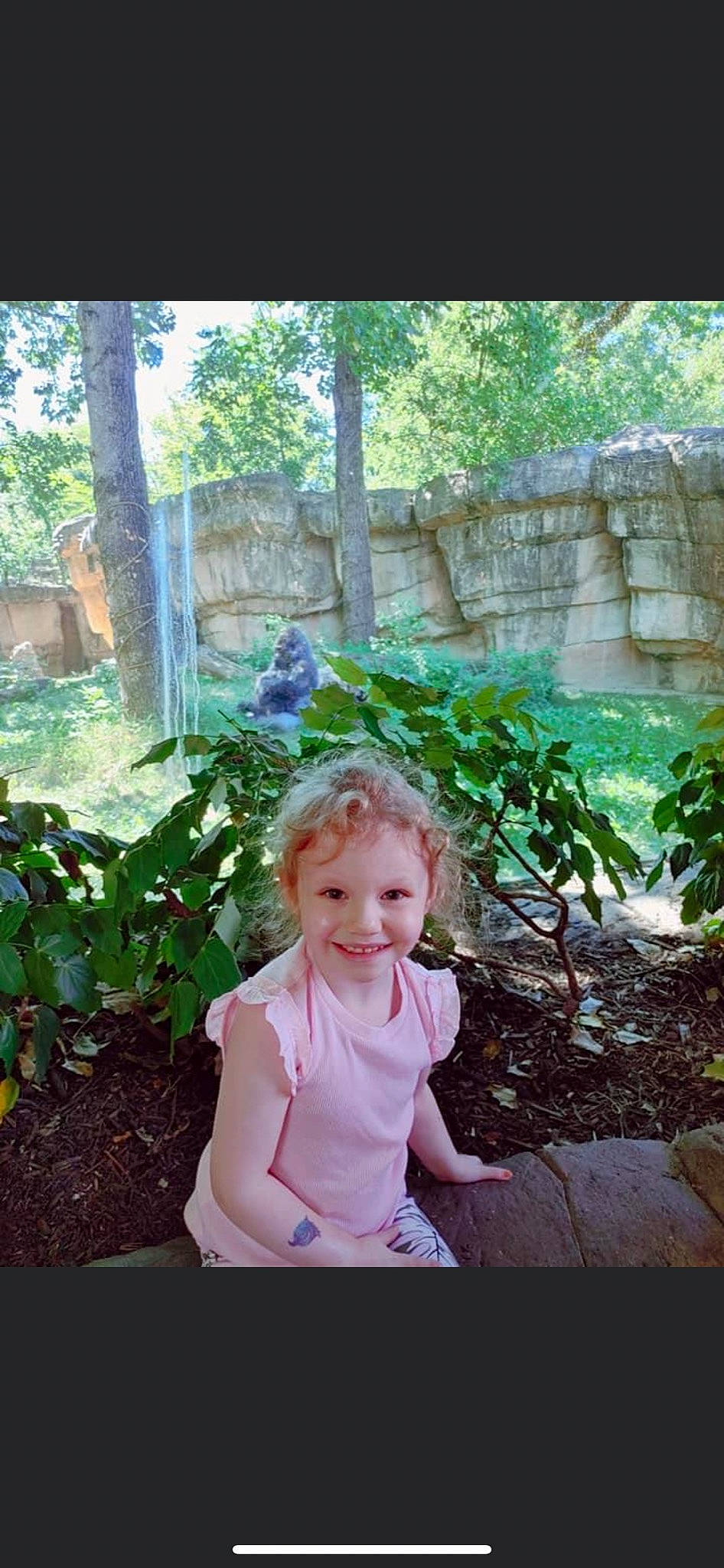 Kennedy is registered to the contest to win money with this photo: baby_toddler_clothing, child, eye, forest, fun, garden, grass, happy, joy, jungle, landscape, leisure, people_in_nature, person, plant, shrub, sitting, smile, terrestrial_plant, toddler