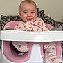 baby, infant, smiling, pink_onesie, baby_seat, high_chair, ingenuity_brand, face, happy, child, cute, indoor, cushions, patterned_background, person, seated, clothing, head, eyes, mouth