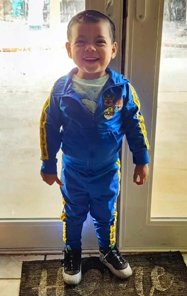 William joined the competition — help win amazing prizes! child, toddler, smiling, blue_tracksuit, yellow_stripes, cartoon_patches, sneakers, standing, indoor, glass_door, doormat, happy, casual_clothing, person, floor_tiles, short_hair, full_body, daylight, home, front_door