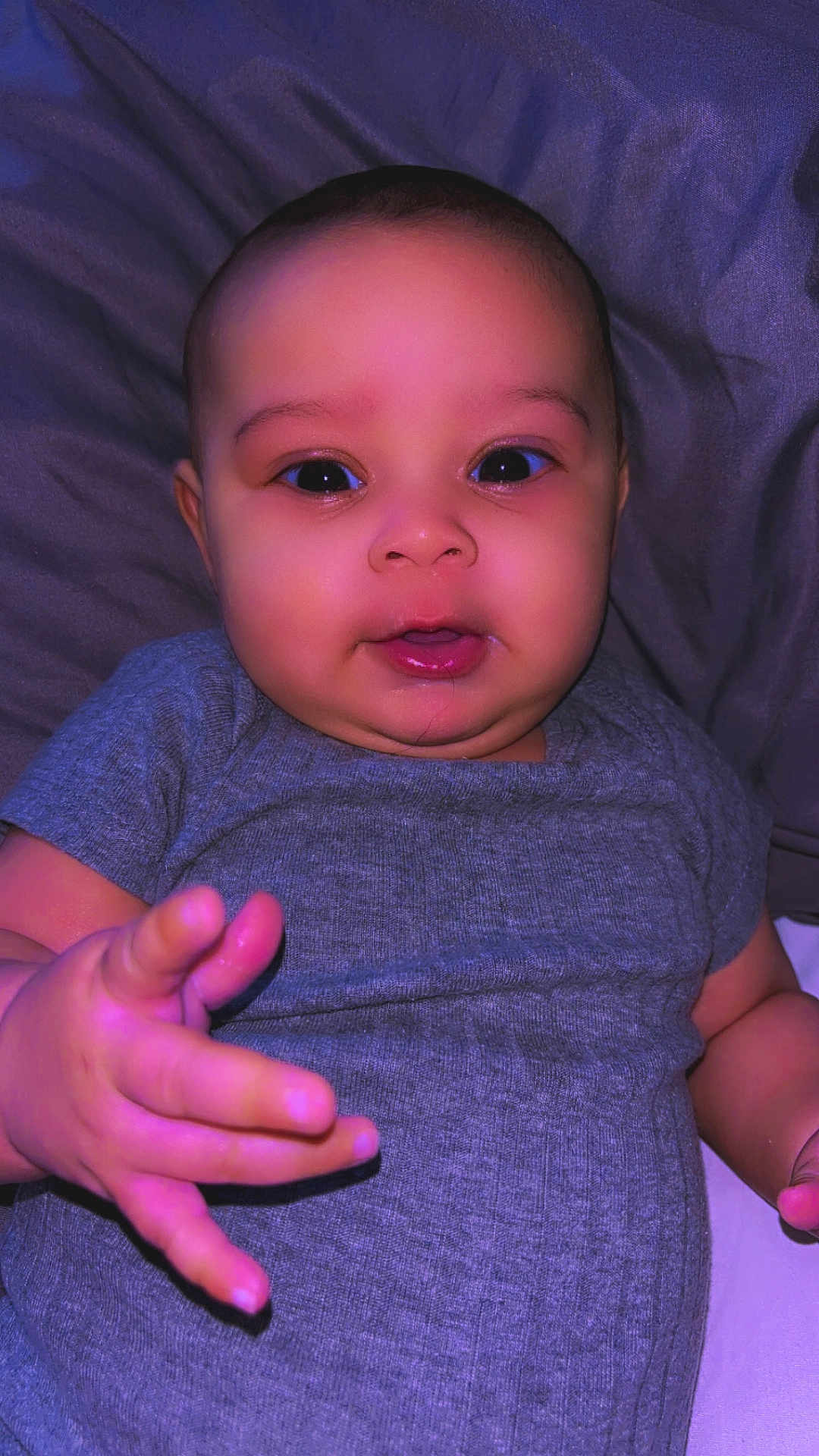 Arielis is registered to the contest to win money with this photo: baby, bed, blanket, cheeks, child, chubby, closeup, cute, eyes, face, hand, indoor, infant, mouth, onesie, pillow, portrait, purple_tint, smile, soft_lighting