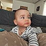 Noah participe au concours pour gagner de l'argent avec cette photo : baby, infant, striped_clothing, couch, cushion, indoor, child, face, cheeks, looking_away, hand, onesie, soft_lighting, home, living_room, curious, young_child, portrait, furniture, relaxed