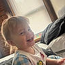 Kase is registered to the contest to win money with this photo: toddler, child, smiling, indoors, bed, window, blinds, natural_light, clothing, bib, pajamas, happy, face, hair, person, young_child, portrait, sitting, room, cozy