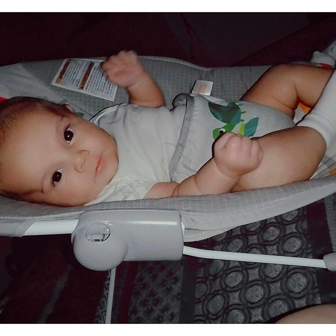 Jaden joined the competition — help win amazing prizes! baby, baby_rocker, blanket, child, clothing, colorful, cozy, cute, face, furniture, indoor, infant, lying_down, patterned, person, playful, portrait, resting, socks, soft_lighting