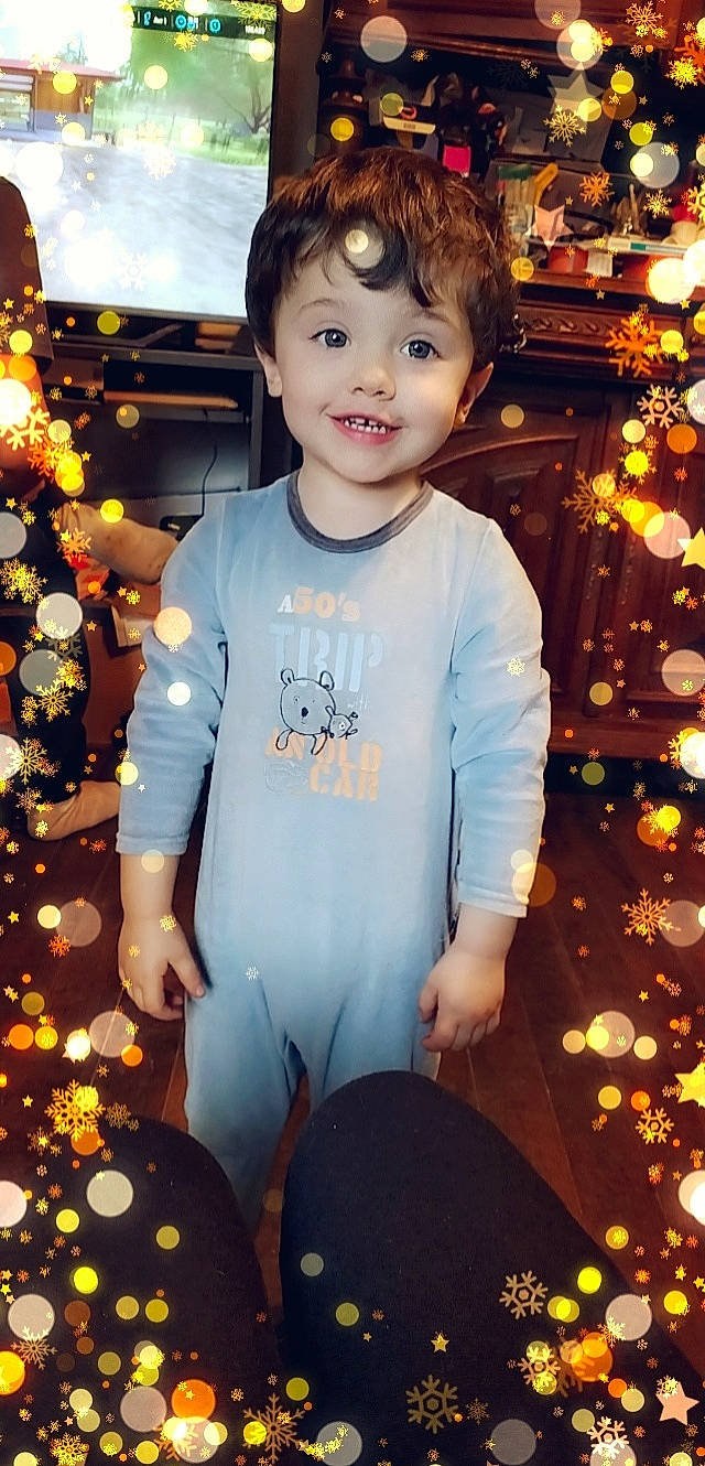 Tiago participe au concours pour gagner de l'argent avec cette photo : baby_toddler_clothing, christmas, christmas_decoration, christmas_ornament, event, facial_expression, flash_photography, fun, hair, happy, holiday, joy, leaf, orange, people_in_nature, person, plant, sleeve, smile, standing