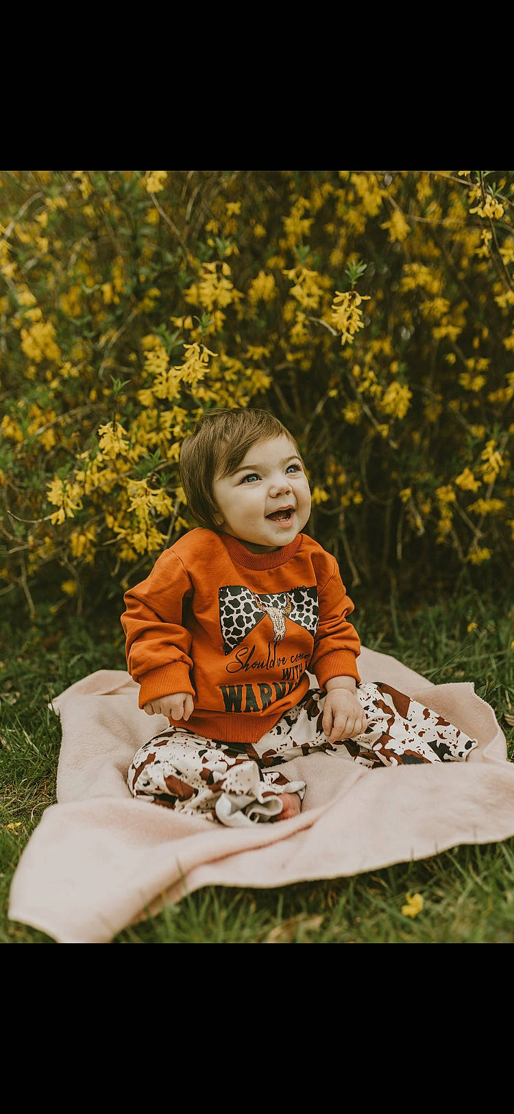 Shae is registered to the contest to win money with this photo: baby, baby_toddler_clothing, beauty, child, dress, facial_expression, grass, happy, leisure, nature, orange, pattern, people_in_nature, person, plant, sitting, smile, t_shirt, toddler, tree