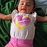 Thalia is registered to the contest to win money with this photo: baby, child, infant, toddler, clothing, shirt, pants, nike_logo, heart, lying_down, blanket, green, pink, white, face, arms, relaxed, indoor, cute, portrait