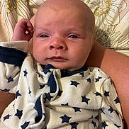 Ethan is registered to the contest to win money with this photo: baby, infant, closeup, face, onesie, star_pattern, sleepwear, blanket, floral_pattern, hand, skin, expression, newborn, lying_down, cute, portrait, child, young, indoors, comfort
