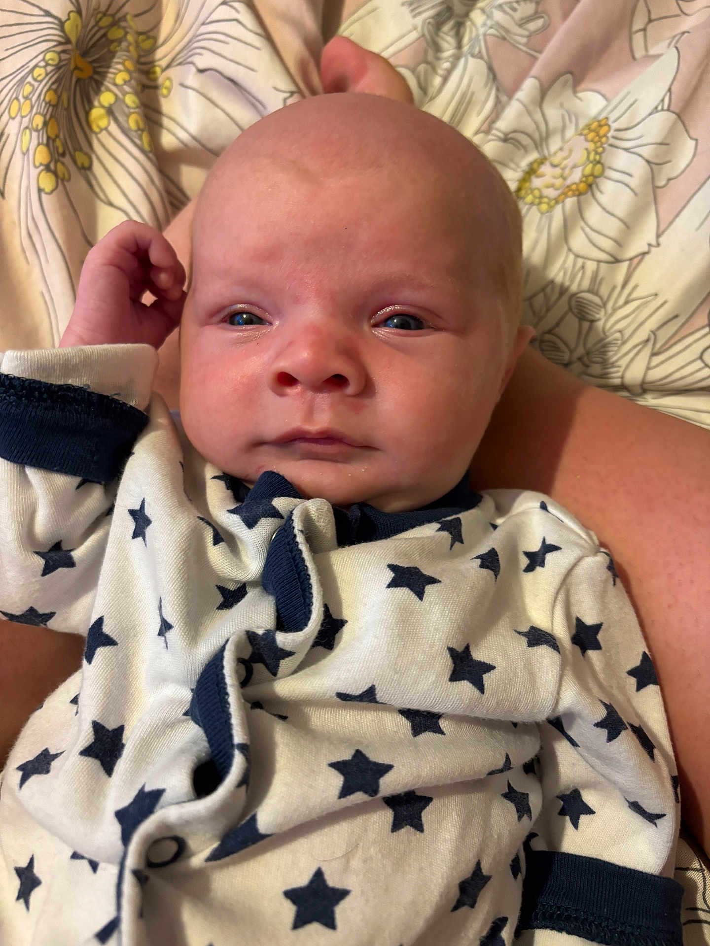 Ethan is registered to the contest to win money with this photo: baby, infant, closeup, face, onesie, star_pattern, sleepwear, blanket, floral_pattern, hand, skin, expression, newborn, lying_down, cute, portrait, child, young, indoors, comfort
