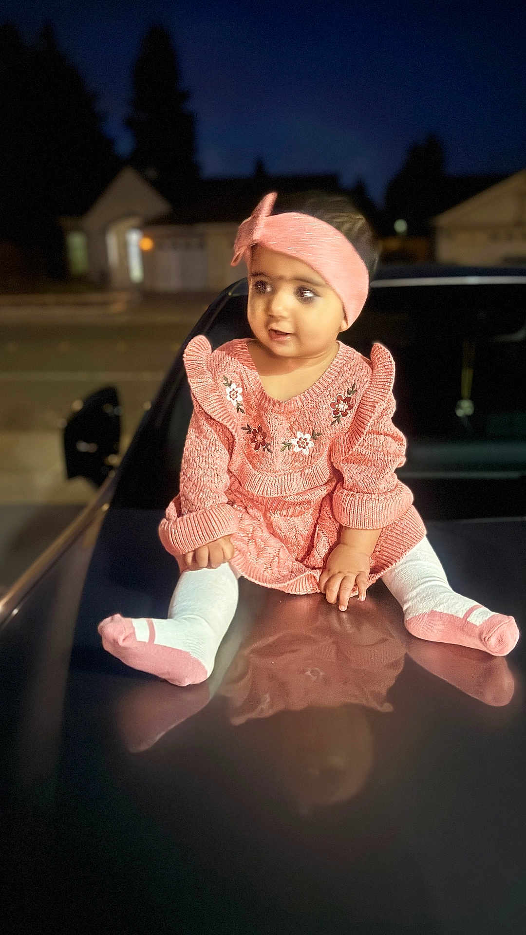 Harish is registered to the contest to win money with this photo: baby, car_hood, child, curious, cute, expression, fashion, feet, headband, knitted_clothing, night, outdoor, person, pink_dress, portrait, reflection, sitting, toddler, warm_clothing, young_child