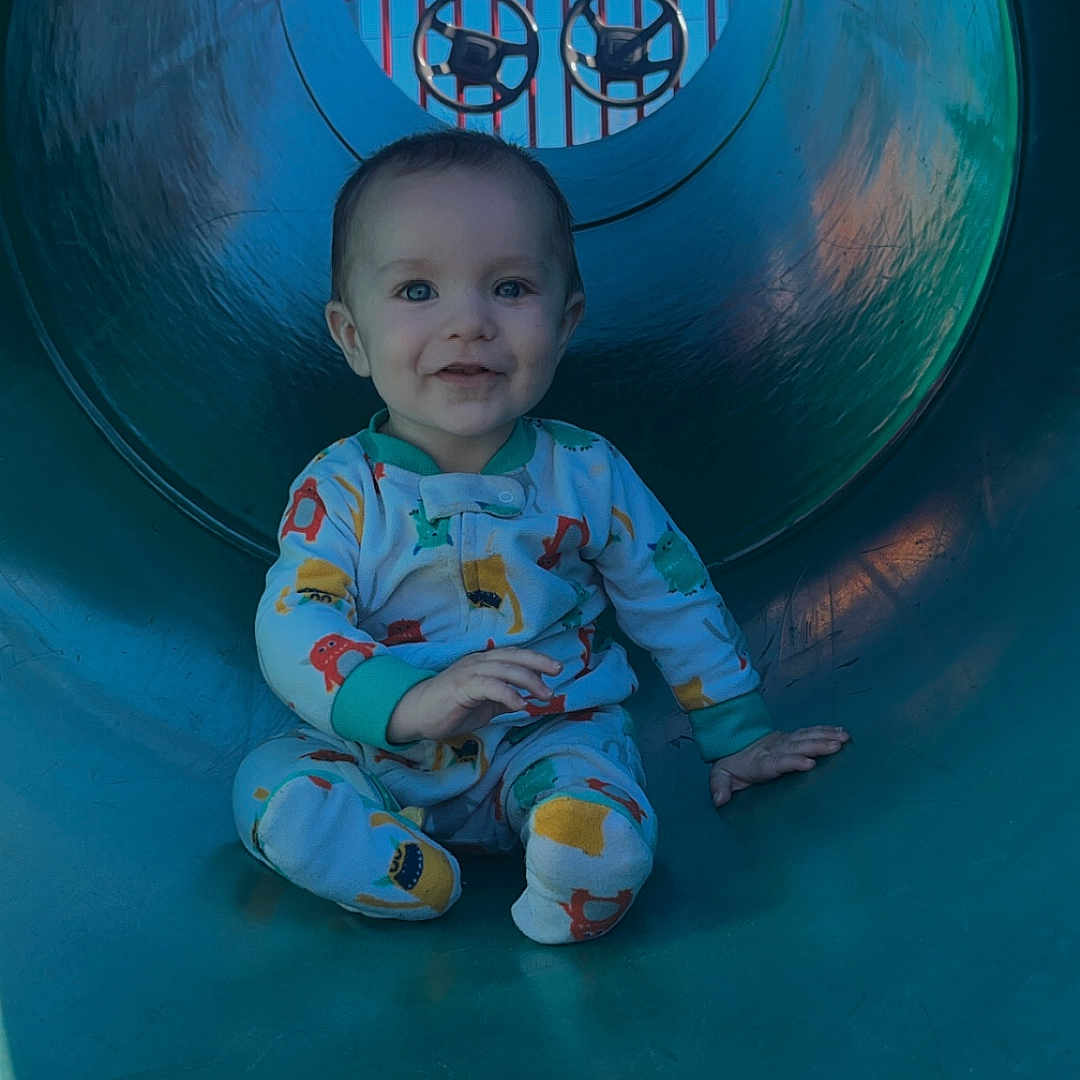 Triton is registered to the contest to win money with this photo: baby, clothing, face, happy, head, hosiery, indoors, outdoorplayarea, outdoors, pajamas, pants, person, photography, playarea, portrait, slide, smile, sock, sphere, toy