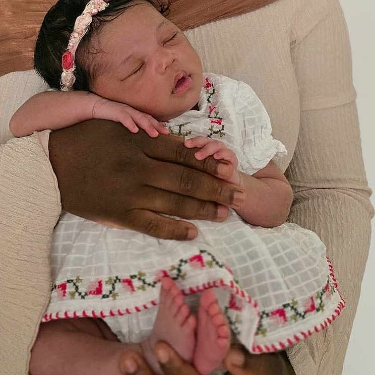 Zaylah is registered to the contest to win money with this photo: adult_hand, baby, care, child, closeup, cradled, embroidered, family, feet, fingers, floral_headband, infant, love, peaceful, portrait, skin, sleeping, tender, warmth, white_dress