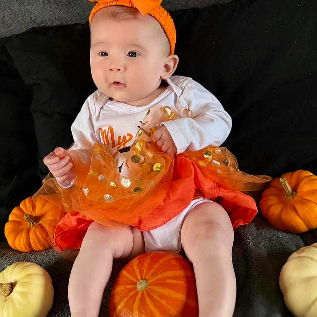 Isla-May is registered to the contest to win money with this photo: baby, citrusfruit, clothing, costume, face, festival, food, halloween, hat, head, person, photography, plant, portrait, produce, pumpkin, sitting, sleeve, squash, vegetable