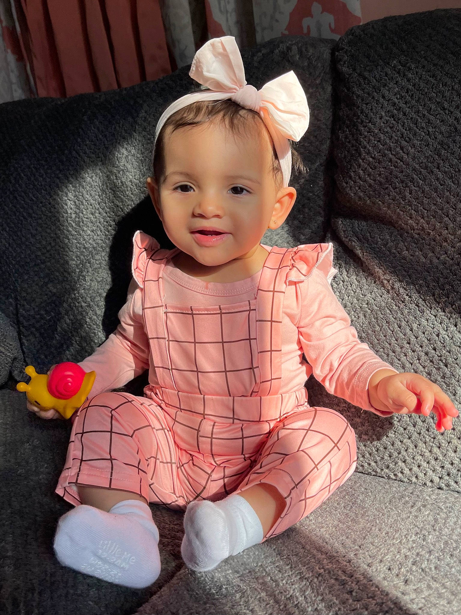 Amiyllah is registered to the contest to win money with this photo: baby, baby_toddler_clothing, cheek, child, comfort, couch, face, happy, human_leg, lap, magenta, pattern, person, pink, skin, sleeve, smile, sock, thigh, thumb