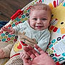 baby, smiling, blue_eyes, baby_seat, colorful, patterned_clothing, hand, infant, toddler, indoor, wooden_floor, happy, cute, playful, person, child, face, seated, toy, animal_design