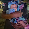 Malia joined the competition — help win amazing prizes! baby, child, infant, costume, blue, purple, sparkly, hat, wings, smiling, wide_eyed, portrait, being_held, adult, parent, nighttime, outdoor, event, crowd, pavement