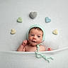 baby, infant, newborn, blanket, knitted_hat, heart_shapes, soft_texture, pastel_colors, cute, portrait, smiling, headwear, lying_down, cozy, child, innocence, warmth, white_background, peaceful, adorable