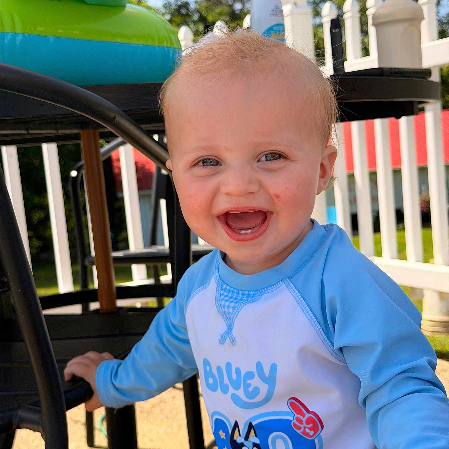 Raiden Dale Secrest is registered to the contest to win money with this photo: baby, bluey, child, clothing, daylight, expression, face, fence, fun, hair, happy, outdoor, person, playground, shirt, skin, smiling, sunlight, toddler, toy