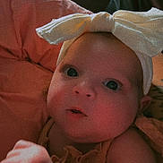 Aurora is registered to the contest to win money with this photo: baby, child, face, headband, bow, looking, curious, closeup, portrait, infant, skin, hand, soft, warm_lighting, expression, clothing, indoors, young, cute, person