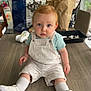 toddler, child, baby, sitting, table, overalls, white_shoes, socks, red_hair, blue_eyes, indoor, wooden_table, bags, plant, chair, window, furniture, casual_clothing, portrait, home