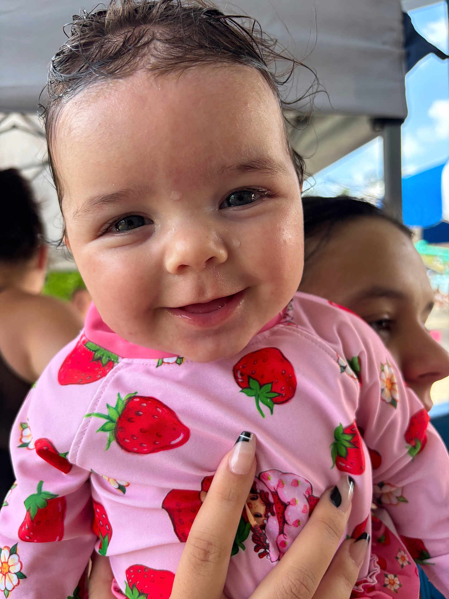 Laynie joined the competition — help win amazing prizes! baby, child, person, smile, face, pink_clothing, strawberry_pattern, wet_hair, hand, manicure, outdoor, tent, sky, happy, cute, portrait, closeup, holding, people, background
