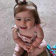 Khloe is registered to the contest to win money with this photo: baby, child, smiling, sitting, carpet, toy, playing, happy, cute, indoors, person, infant, hair_tie, pink_clothing, legs, feet, face, expression, young, fun