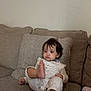 toddler, child, pajamas, couch, sofa, indoor, face, foot, curly_hair, blanket, neutral_expression, home, furniture, comfort, relaxing, infant, person, seated, cozy, casual